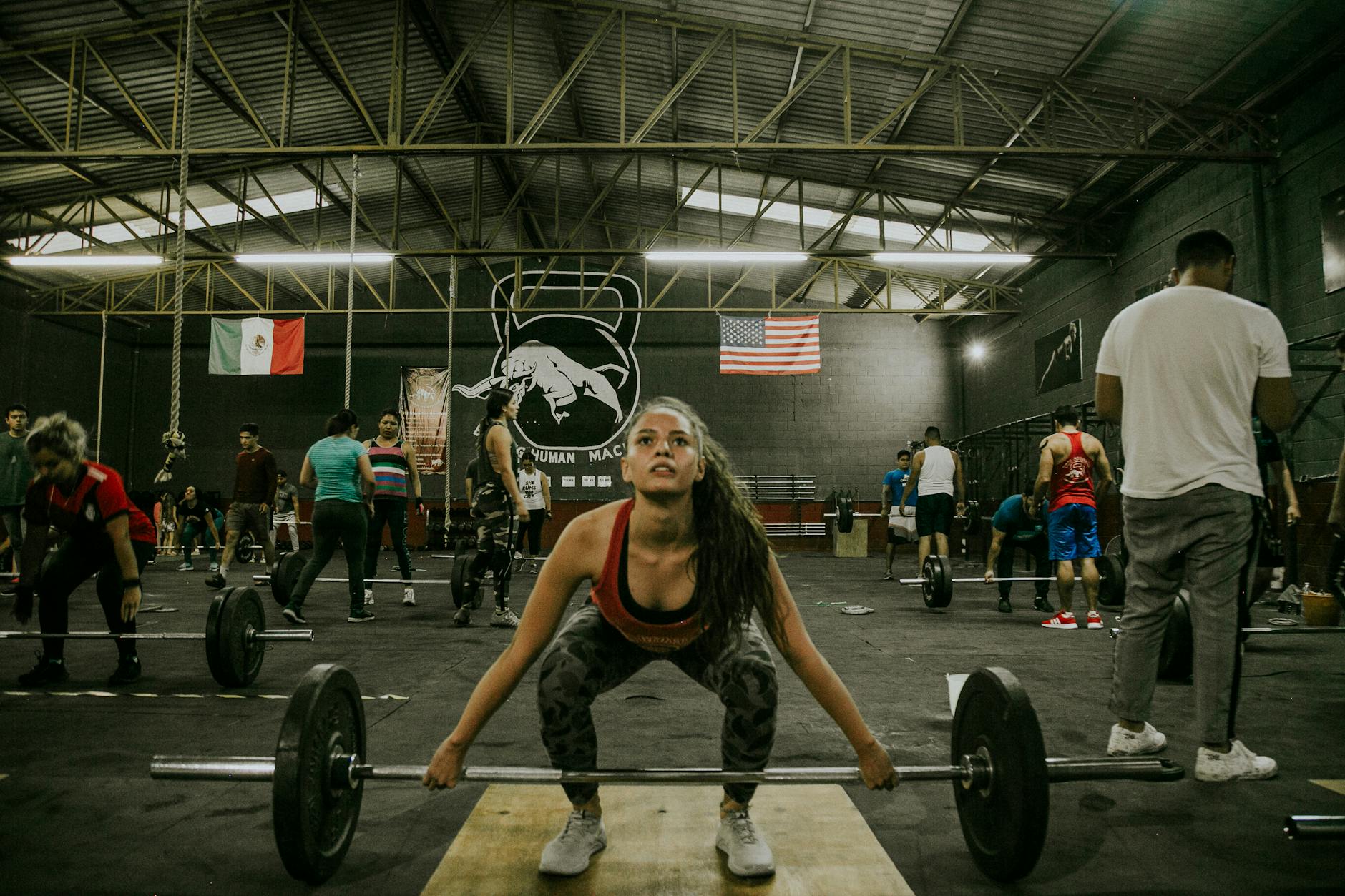 Grupa osób ćwiczy crossfit z ciężarami na siłowni